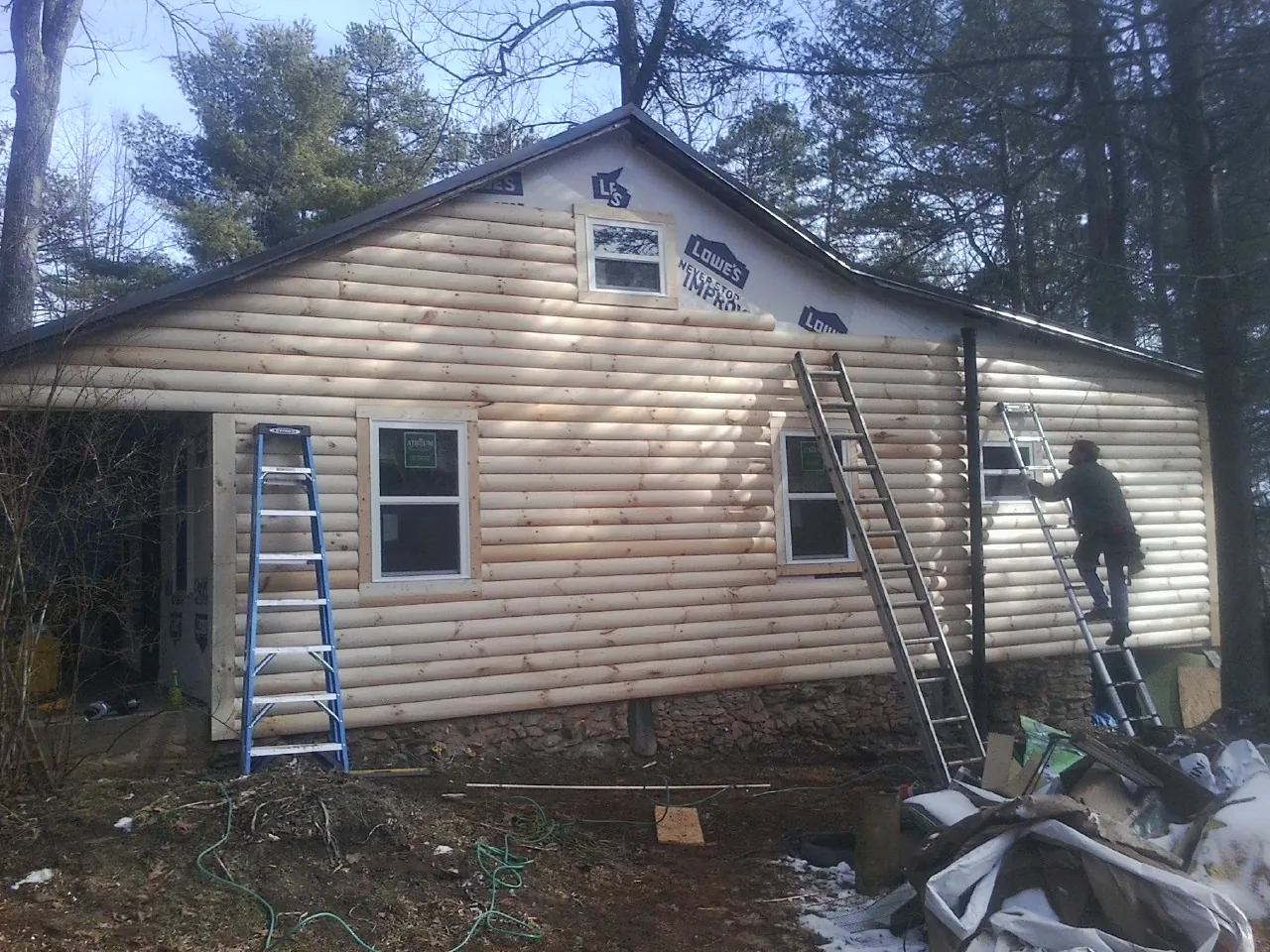 Ladders set against fresh log siding during an exterior remodel in Spofford