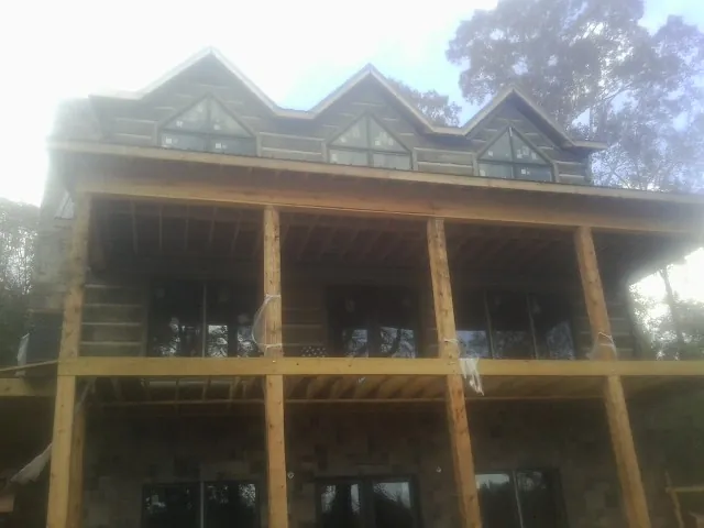 Dormers and porch framing on a large log home under construction — Roof Coating work by our crew in Spofford