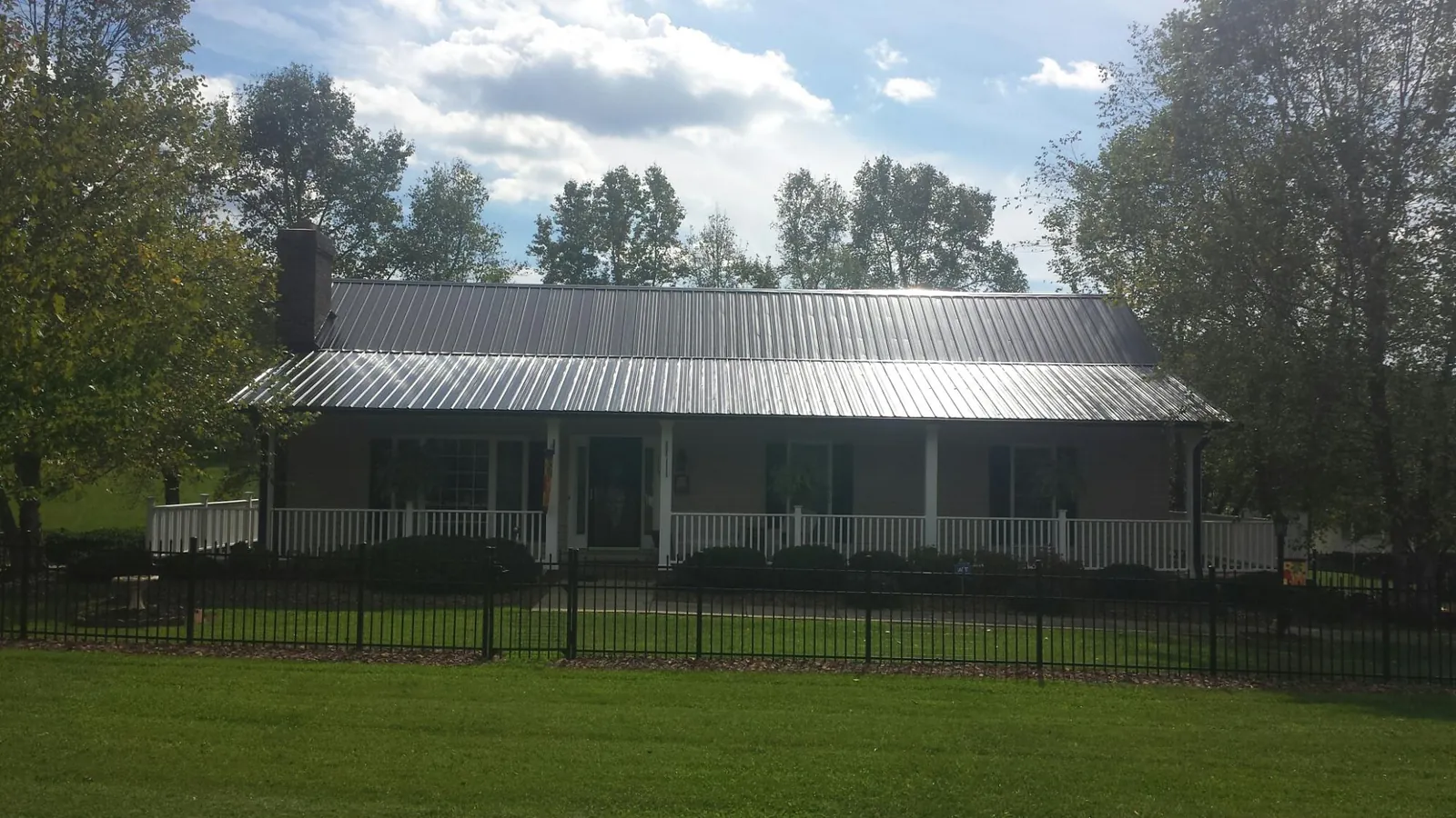 Gray metal roof on a brick ranch with a full width front porch — Gutter Guard Installation work by our crew in Spofford
