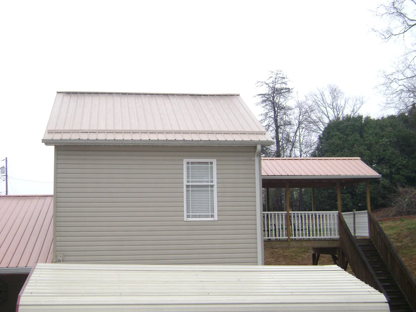 Tan metal roofs on a two story addition and attached porch, from a Roof Replacement job in Spofford