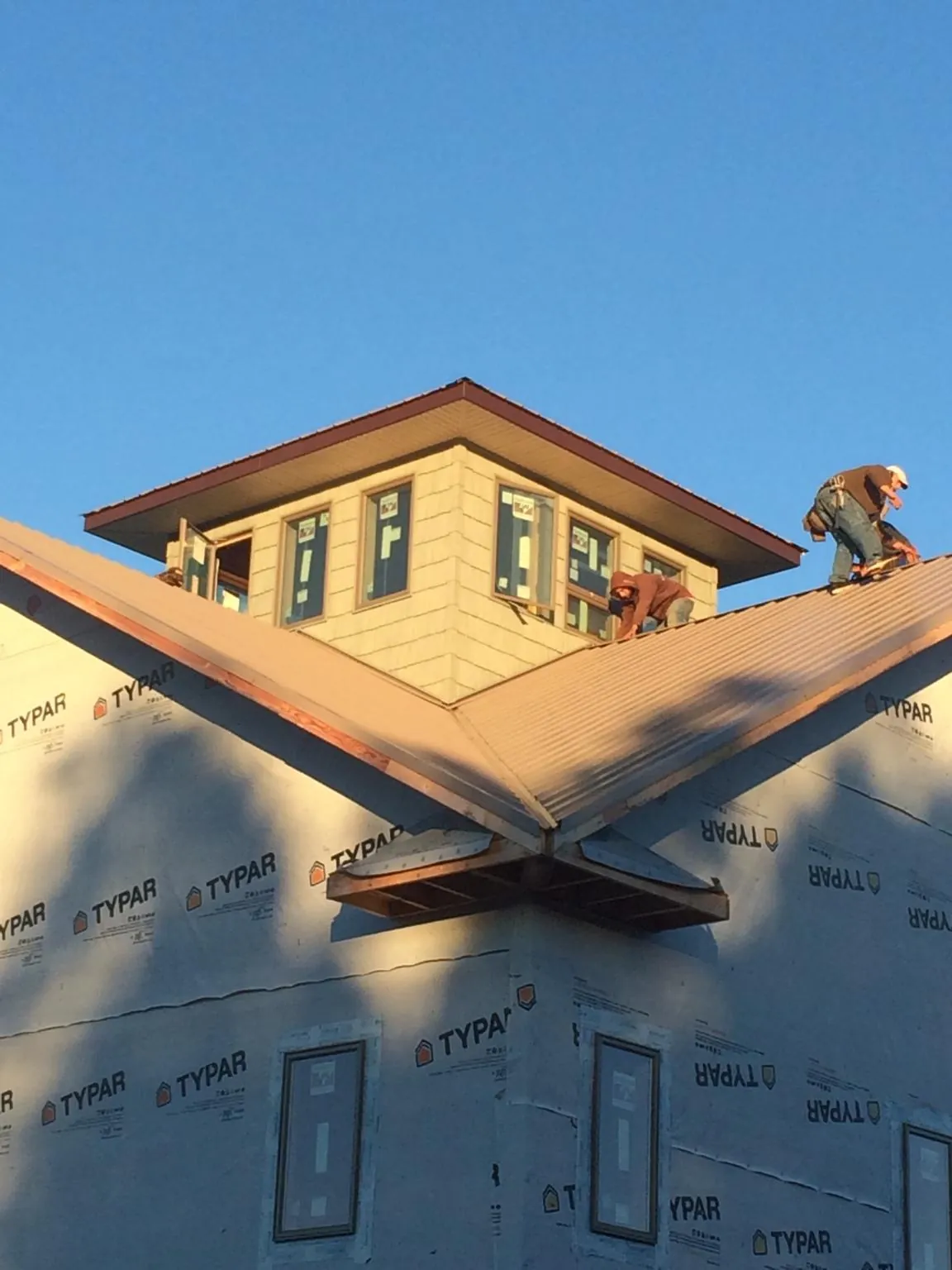 Roofers working around a rooftop cupola on a new metal roof at sunset — Roof Waterproofing in Spofford by Roofing Brothers